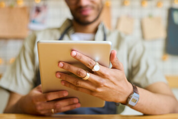 Aufkleber - Hands of young black man holding tablet in front of himself while networking and looking through online orders of clients