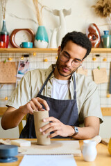 Aufkleber - Creative male pitcher making new clay vase or jug while sitting by table with supplies for creatibe earthenware in studio or workshop
