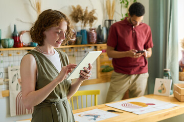 Aufkleber - Young interracial coworkers using mobile gadgets while taking photo of drawing and working over new creative project in studio
