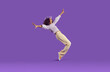 Cheerful joyful african american teenage girl having fun getting on her toes on purple background. Funny stylish preteen girl fooling around, rejoicing and laughing out loud. Full height. Banner.