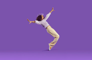 cheerful joyful african american teenage girl having fun getting on her toes on purple background. f