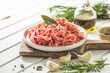 Fresh Raw Beef Minced Meat with herbs and rosemary on wooden board on a light background, banner, menu, recipe place for text, top view,