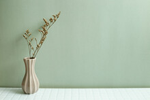 Vase Of Dry Flowers On White Table. Khaki Green Wall Background