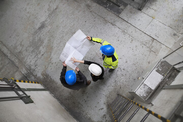 Sticker - Top view of engineer and industrial worker in uniform shaking hands in large metal factory hall and talking.