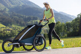 Fototapeta Las - Active family concept. Fit and healthy mother runs on a track while pushing a stroller