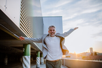 Portrait of happy energetic mature businessman with arms outstretched balancing on wall , feeling free, work life balance concept.