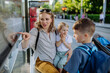 © Halfpoint - Young mother with little kids waiting on bus stop in city.