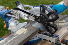 Miter Circular Saw Photographed In The Process Of Work. Tool For Carpentry. A Man Works With A Tool. The Worker Saws The Boards. Sawmill. Miter Saw For Cutting Wood At Work.