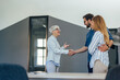 © bnenin - A mature businesswoman finished a meeting with a young couple, leaving the office, shaking hands.