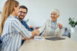 © bnenin - Businesswoman shaking hands with a female client, finished meeting with a young couple.