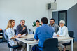 © bnenin - Businesspeople sitting around the table, having a meeting, listening to their boss.