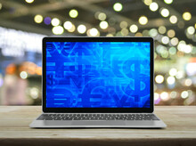 Financial Currency Symbol On Modern Laptop Computer Monitor Screen On Wooden Table Over Blur Light And Shadow Of Shopping Mall