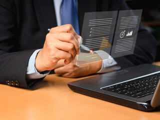 Electronic signature and paperless office concept. A businessman uses a pen to sign documents on a virtual screen