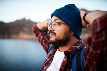 a close up of hiking man admiring the lake view while backpacking the mountains