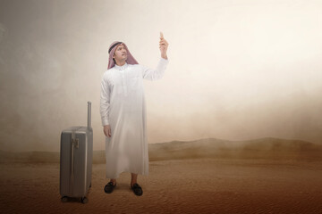 Poster - Arab man wearing keffiyeh looking at mobile phone with a suitcase for traveling