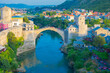 Fantastic Skyline of Mostar with the Mostar Bridge, houses and minarets, during sunny day. Location: Mostar, Old Town, Bosnia and Herzegovina, Europe