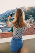 © Bevan G/peopleimages.com - Woman taking photos of Italy coast using smartphone. Rear view of woman taking pictures of ocean view on vacation