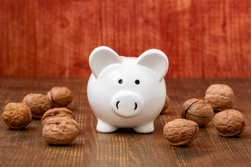 Wall Mural - Ceramic piggy bank and walnuts on wooden background