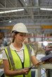 Female warehouse worker Counting items in an industrial warehouse on the factory's mezzanine floor. which is a storage for small and light electronic parts.