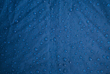Rainwater Drops On A Blue Background Made Of Waterproof Fabric. Texture And Abstract Background.