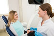 © Tania - A beautiful female dentist is talking to a patient while sitting in a chair.
