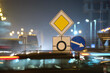 Leinwandbild Motiv Roundabout road signs with blurred cars on city street traffic at night. Urban transportation concept