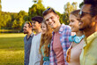 © Studio Romantic - Portrait of joyful young man standing with his friends hanging out in public park. Cropped shot of group of cheerful multiracial friends gathered together in park on sunny summer day. Selective focus.