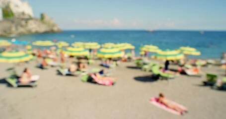 Wall Mural - A group of various people spending time on the beach to catch a tan. A blurred group of people relaxing on the beach