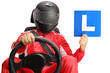 Racer with helmet in a car seat holding a learner plate