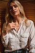 Delicate and sensual blonde in a white silk blouse and with a decoration around her neck