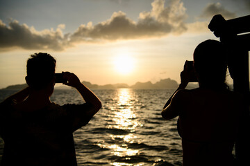 Dos personas observan la Puesta de sol El Nido en la isla de Pinagbuyutan, vistas naturales del paisaje kárstico, acantilados. Palawan, Philippines. Viajes de aventura.