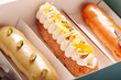 Set of eclair cakes with different fillings in a box close-up. Traditional french dessert