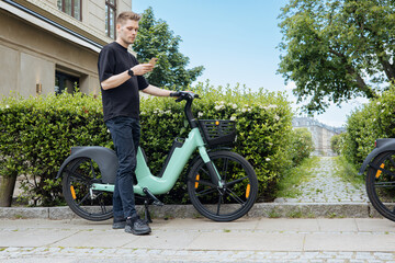 Young man unlocking a bike. Sustainable mobility transport New way of inclusive cities mobility. Green transportation. Sustainable climate neutral city bike goals. Green mobility and transportation