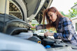 © waranyu - woman checking oil level in a car, change oil car