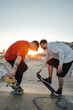 Shot of two tattooed hipster boys skateboarding at skate park at sunset.