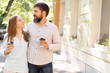 © Andrii Lysenko - Positive young couple with takeaway coffee walk enjoying conversation while toothy smiling and looking at each other, relationship and lifestyle concept