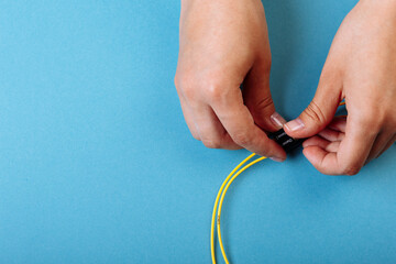 Wall Mural - Hands prepare to tune a variable optic attenuator with a screwdriver. Blue background