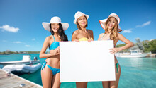 Travel, Tourism And Summer Vacation Concept - Happy Women In Bikinis Holding Blank White Board Over Wooden Pier And Boat On Tropical Beach Background In French Polynesia