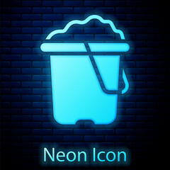 Poster - Glowing neon Sand in bucket icon isolated on brick wall background. Plastic kid toy. Summer icon. Vector