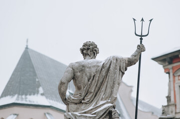 A fragment of the fountain of Neptune with a trident in his hand in the historic center of the city. Lvov, Ukraine. View from the back.