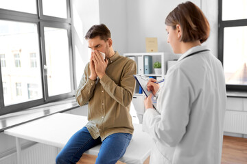 Poster - medicine, healthcare and people concept - female doctor with clipboard talking to man patient blowing his nose with paper tissue at hospital