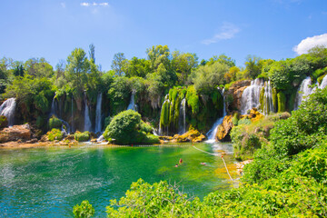 Small boat rowing just under Kravica waterfalls in southern Bosnia and Herzegovina