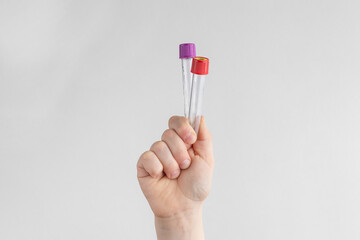 child hand holding two test tubes. white and gray background with copy space. concept of health