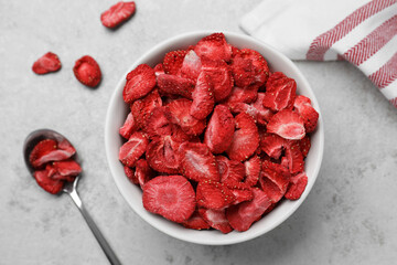 Wall Mural - Bowl and spoon with dried strawberries on light grey table, flat lay