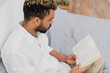 © LIGHTFIELD STUDIOS - high angle view of young african american man with dyed hair reading book in bedroom.