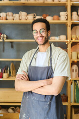 Aufkleber - Happy young male pitcher or clerk of small earthenware shop looking at you while standing against display with handmade clay items