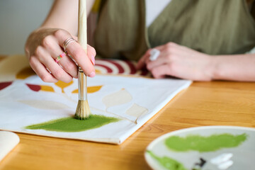Aufkleber - Hand of young creative female artist with paintbrush putting green watercolor on paper while creating new abstract painting