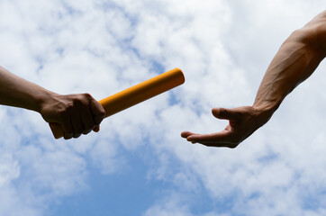 Wall Mural - Close up hand set baton from hand to hand on sky background. Business concept for teamwork and team builder.