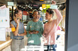 © Wavebreak Media - Multiracial female colleagues discussing business strategy on glass wall in office
