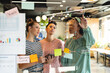 © Wavebreak Media - Multiracial female colleagues discussing business strategy on glass wall in office
